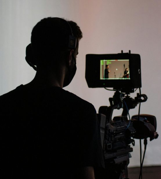 Silhouette of a cameraman operating professional video equipment in a studio setting.
